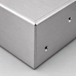 Close-up of precision 90-degree bend corner on brushed aluminum sheet metal amplifier chassis