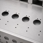 Close-up of laser-cut vacuum tube socket holes on brushed aluminum amplifier chassis